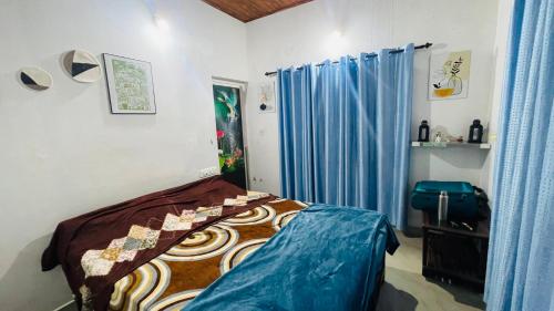 a bedroom with a bed and a blue curtain at Munnar Hills And Mist Views in Anachal