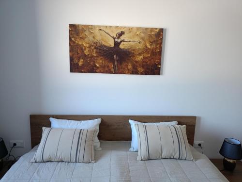 a bedroom with a bed with a painting on the wall at A-Apartman in Bjelašnica