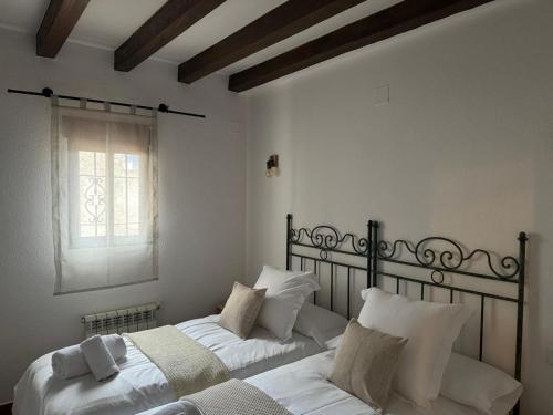 a bedroom with two beds with white sheets and a window at Alojamientos Messía de Leiva in Segura de la Sierra