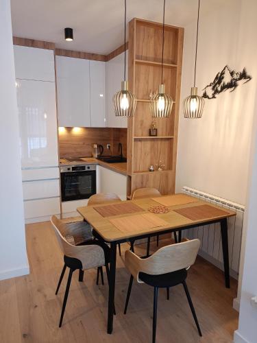 a kitchen with a wooden table and chairs at A-Apartman in Bjelašnica