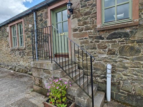 a stone house with a staircase and flowers in front of it at 2 Bed in Biggar 95516 in Biggar