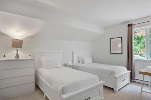 a white bedroom with two beds and a window at Aiglon by Rendez-Vous Mont-Tremblant in Mont-Tremblant