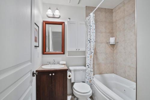 a bathroom with a toilet and a tub and a sink at Aiglon by Rendez-Vous Mont-Tremblant in Mont-Tremblant
