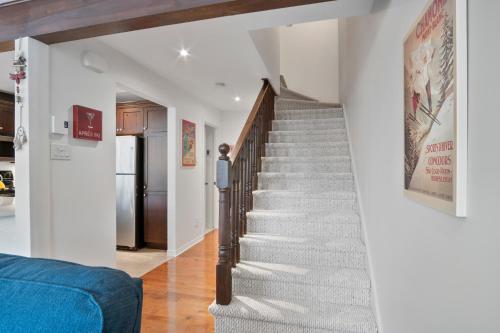 a staircase in a home with white walls and a blue couch at Aiglon by Rendez-Vous Mont-Tremblant in Mont-Tremblant