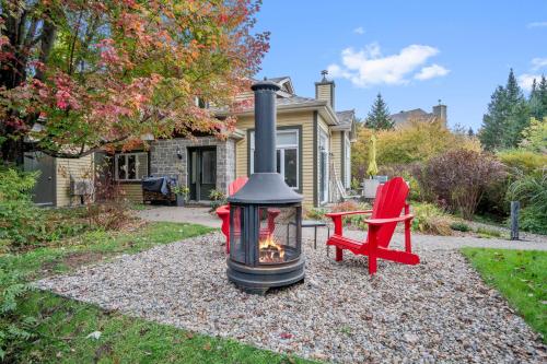 a fire pit and a red chair in front of a house at Aiglon by Rendez-Vous Mont-Tremblant in Mont-Tremblant