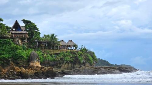 a house on a cliff next to the ocean at Monkey House Hostel in Tola