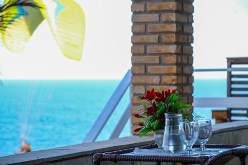a table with wine glasses and a vase with flowers at Casa Vista ao Mar - Paisagem Deslumbrante e Localização Perfeita in Canoa Quebrada