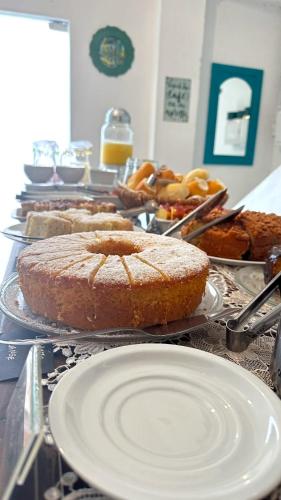 a table with several different types of cakes and bread at Pousada Manjericão in Paraty