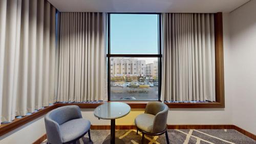 a room with chairs and a table and a window at How inn Hotel in Al Madinah