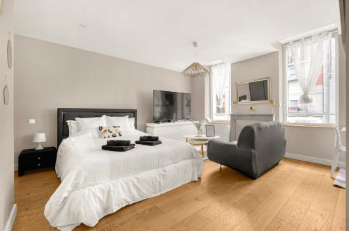 une chambre blanche avec un grand lit et une chaise dans l'établissement La Perle Colombette- Studio Élégant - Hyper Centre, à Toulouse