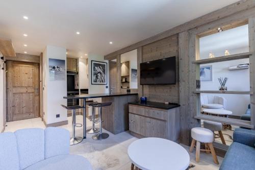 une cuisine avec un bar et des chaises et une télévision dans l'établissement Grand Sud - Cosy two bedroom ski in and out, à Mussillon