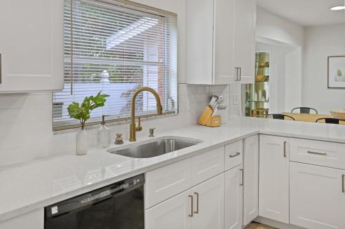 a white kitchen with a sink and a window at Golden Retreat: Expansive 6BR Home w Heated POOL ~ in Seminole