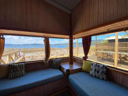 a screened in porch with benches and a view of the ocean at Vichuquen Lodge y Marina in Vichuquén