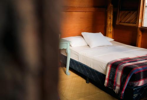 a bed with a wooden headboard and a table at Casa Madera in San Marcos La Laguna