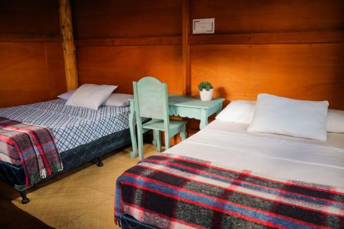 a bedroom with two beds and a table and a chair at Casa Madera in San Marcos La Laguna