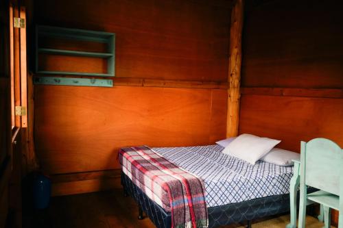 a small bed in a room with a wooden wall at Casa Madera in San Marcos La Laguna