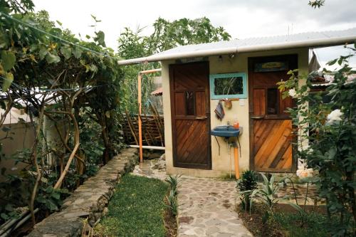 a small house with a wooden door in a garden at Casa Madera in San Marcos La Laguna