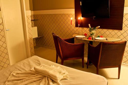 Cette chambre comprend une table, un lit, une table et des chaises. dans l'établissement Hotel & Motel Henrique Dias (Adults Only), à Récife