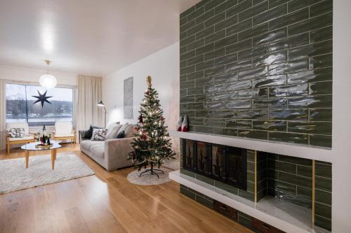 a living room with a fireplace with a christmas tree at Northern Lights River in Rovaniemi