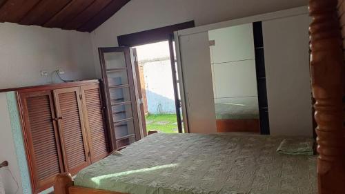 Un dormitorio con una cama y un espejo grande. en Jardim Aruan, Caraguatatuba ,sp, en Caraguatatuba
