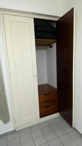 a closet with white doors and a wooden drawer at Apartamento Matteo in Ubatuba