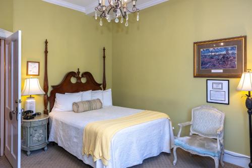a bedroom with a bed and a chair and a chandelier at Eliza Thompson House, Historic Inns of Savannah Collection in Savannah