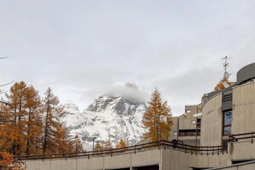 a snow covered mountain in the distance with trees and buildings at Cervino View, Ski-In and WiFi! in Breuil-Cervinia