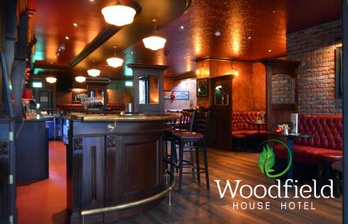 eine Bar in einem Pub mit roten Sitzen in der Unterkunft Woodfield House Hotel in Limerick