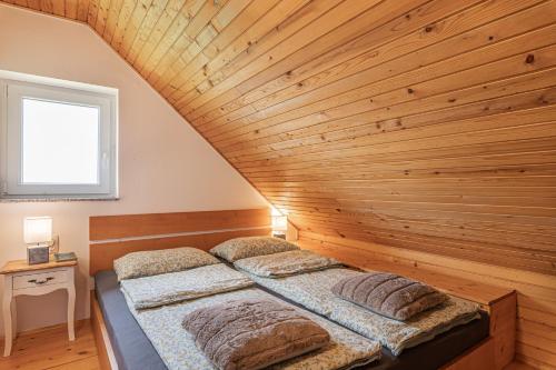 two beds in a room with a wooden ceiling at Holiday House Podhamer Boris with private Wellness in Ljutomer