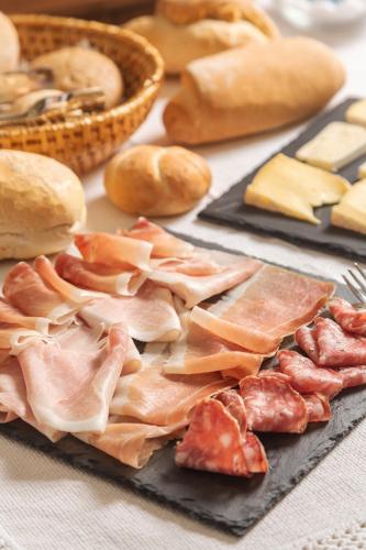 a table topped with different types of meats and bread at Chalet La Felce in Carisolo