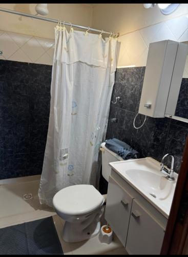 a bathroom with a toilet and a shower curtain at Quinta "La Calma" in Puerto Iguazú