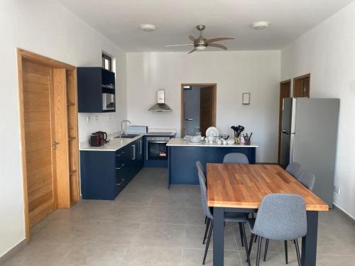 a kitchen with a wooden table and blue cabinets at Canonniers Luxury Stay in Pointe aux Cannoniers