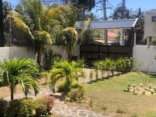 a garden with palm trees and a house at Canonniers Luxury Stay in Pointe aux Cannoniers