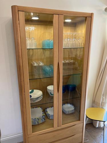 a wooden cabinet with plates and glasses in it at The Exclusive 6 bedroom Farm House, Markington incl heated pool and The Richmond Hill one bedroom Cottage in Ingerthorpe