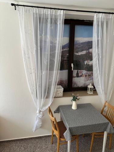 a table and chairs in a room with a window at Penzion Lukeš in Vítkovice