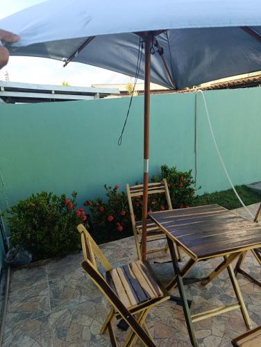 a wooden table and chairs under an umbrella at Casa lagoa dos tambaquis in Estância