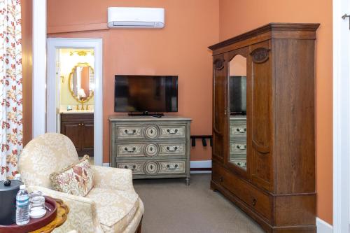 a living room with a tv and a dresser at Eliza Thompson House, Historic Inns of Savannah Collection in Savannah