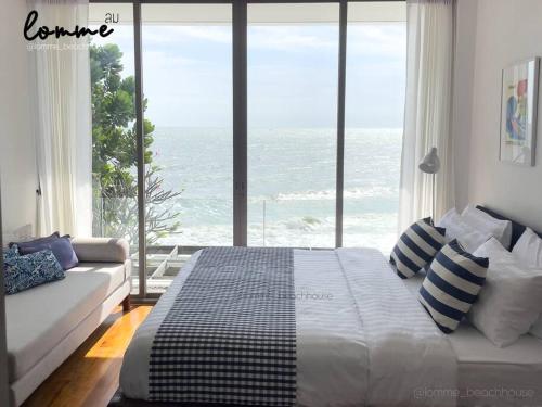 a bedroom with a bed and a view of the ocean at lomme Private Beach House in Cha Am