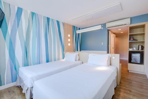 two beds in a room with a window at Mercure Rio de Janeiro Barra da Tijuca in Rio de Janeiro