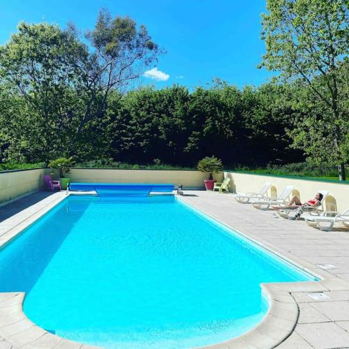 une piscine avec des chaises longues et une piscine dans l'établissement Gîte Cornouaille piscine ou jacuzzi, à Saint-Évarzec