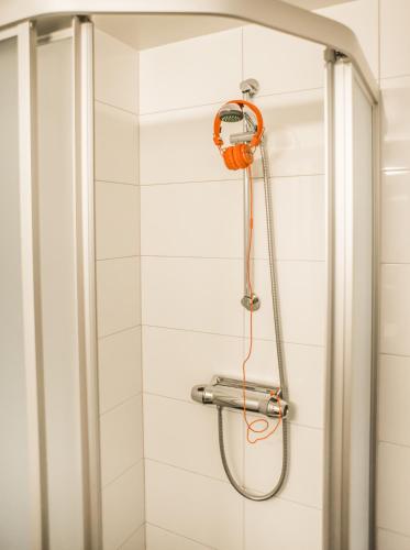 a shower with an orange shower head in a bathroom at Hotell Hulingen in Hultsfred