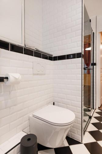 La salle de bains blanche est pourvue de toilettes et d'une douche en verre. dans l'établissement Montmartre Rue des Martyrs Loft with AC, 4-7 PEO, à Paris