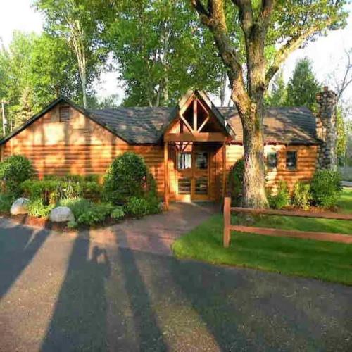 a log cabin with a tree in front of it at Shanty Creek, Condo, Golf ,Sleeps 4, Pets welcome! in Bellaire