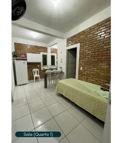 a bedroom with a bed and a kitchen with a table at Condomínio Chalés Santo Antônio - Flecheiras in Trairi