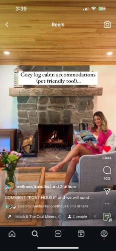 a woman sitting on a couch in front of a fireplace at Haliburton Post House in Minden