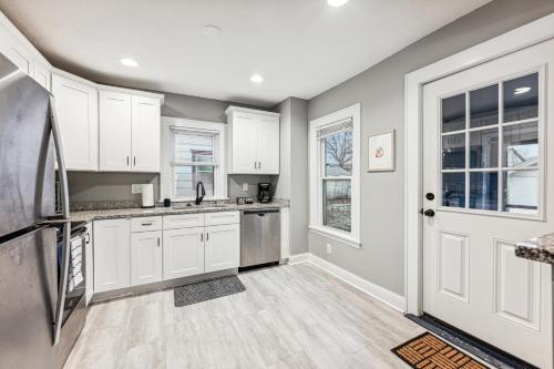 a kitchen with white cabinets and a door at Orange Blossom House - Quaint Family Home 10 Minutes from Downtown MPLS in Minneapolis