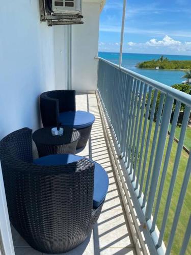 a balcony with two chairs and a view of the ocean at Isleta Marina- Paraíso Costero in Fajardo