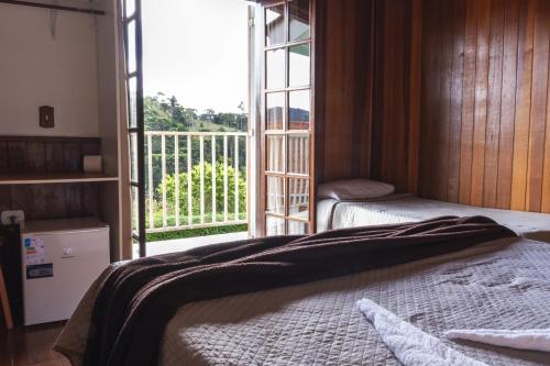 a bedroom with a bed and a large window at Pousada Araucária Suítes in Campos do Jordão