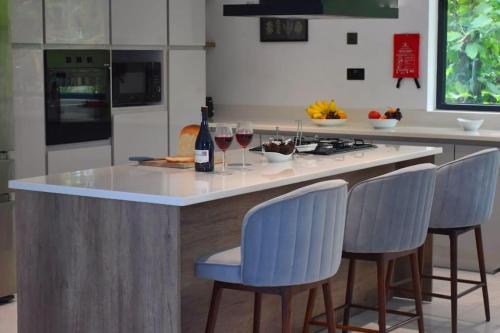 a kitchen with a island with three blue bar stools at The Oriole - Your base to explore Sri Lanka in Battaramulla