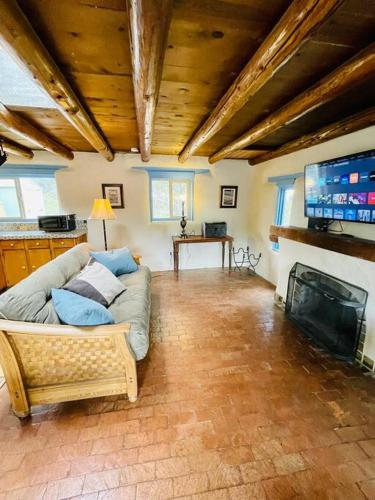 a living room with a couch and a flat screen tv at Casita Azul, Historic and Cozy Santa Fe Adobe in Santa Fe